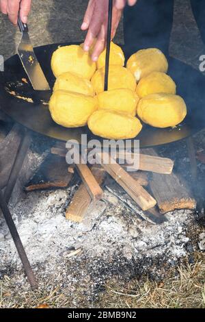 Palle di polenta e formaggio al centro di essa, chiamato bulz, un piatto tradizionale rumeno. Tostatura di polenta e formaggio alla griglia all'esterno, con pecora Foto Stock