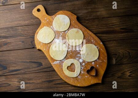 Gnocchi a forma di cuore, farina su fondo in legno. Cottura gnocchi. Vista frontale, primo piano Foto Stock