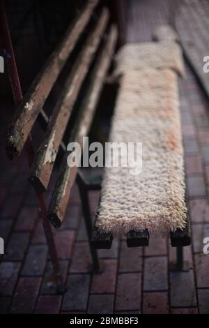 Panca in legno con vernice spellante ricoperta di tappeti Foto Stock