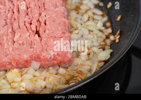 carne tritata fritta in cipolle in una padella nera Foto Stock