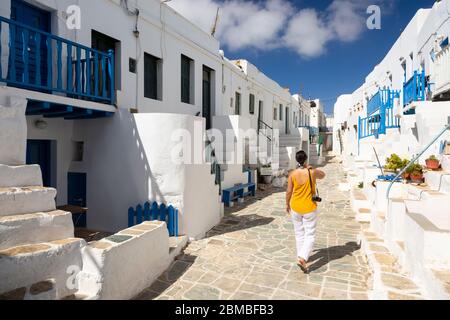 Una donna che cammina lungo una strada passando i tradizionali edifici di imbiancatura a Folegandros, Isole Cicladi, Grecia Foto Stock