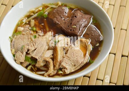 Carne d'anatra bollita e sangue in zuppa di erbe cinesi marroni sulla ciotola Foto Stock