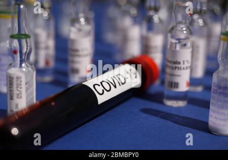 Viersen, Germania - Maggio 8. 2020: Provetta per campioni di sangue con covid-19 isolata tra molte fiale per farmaci per iniezione, sfondo blu (fiala per sangue concentrato) Foto Stock