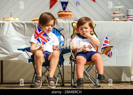 Halesowen, West Midlands, Regno Unito. 8 maggio 2020. I fratelli Zachary (4) e Hugo (2) Hickin godono di una torta a tema del VE Day 75, ognuno dei quali siede nel loro viaggio di fronte ad Halesowen, West Midlands. Credit: Peter Lopeman/Alamy Live News Foto Stock