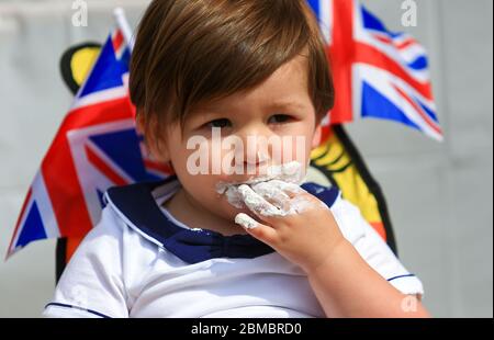 Halesowen, West Midlands, Regno Unito. 8 maggio 2020. Hugo Hickin, 2 anni, gode di una torta a tema del VE Day 75, ognuno dei quali siede nel viaggio di famiglia ad Halesowen, West Midlands. Credit: Peter Lopeman/Alamy Live News Foto Stock