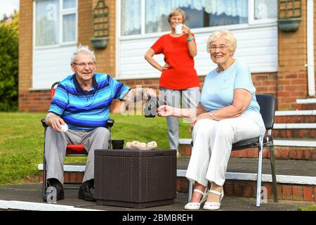 Halesowen, West Midlands, Regno Unito. 8 maggio 2020. Marito e moglie Jean e Michael Towler, 84 e 83, godetevi una fiasca di tè molto inglese con il vicino Stella Worton fuori dalle loro case a Halesowen, West Midlands. Credit: Peter Lopeman/Alamy Live News Foto Stock