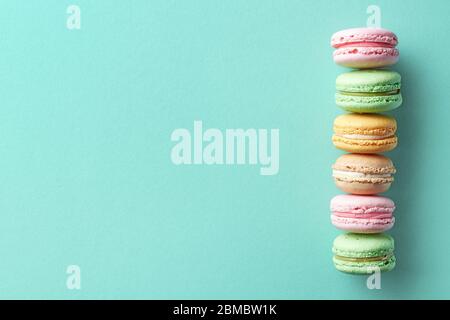 Fila di colorati macaron francesi su sfondo blu. Vista dall'alto. Colori pastello Foto Stock
