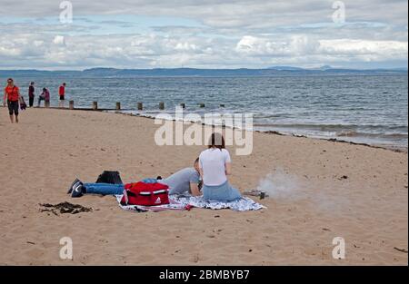 Portobello, Edimburgo, Scozia Regno Unito. 8 maggio 2020. All'osservatore occasionale sembra che alcune persone non stiano prendendo sul serio le distanze sociali come forse lo erano nelle ultime settimane. Anche se la polizia era visibile nel primo pomeriggio, da metà a tardo pomeriggio le persone si trovavano sulla spiaggia e persino una coppia aveva un piccolo barbecue. Credit: Arch White/Alamy Live News. Foto Stock