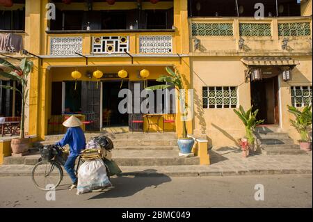 Hoi An, Provincia di Quang Nam, Vietnam - 24 febbraio 2011: Cicli di donne senior nel centro storico di Hoi An, e le sue famose case coloniali gialle Foto Stock