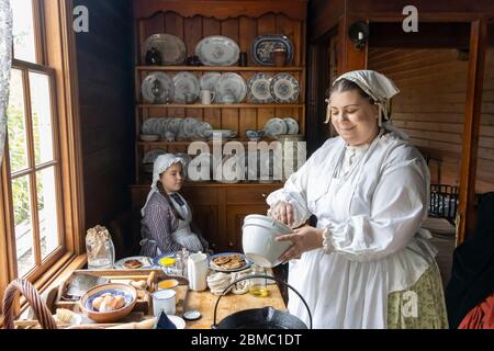 Ballarat, Australia - 7 marzo 2020: Una donna e una ragazza in abiti tradizionali, cucina in una vecchia cucina in una città mineraria dell'oro ricreata. Foto Stock