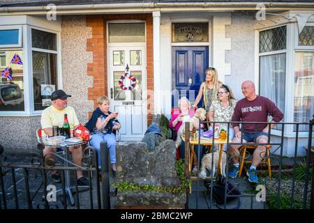 Swansea, Galles, Regno Unito. 8 maggio 2020 le famiglie Jones e Williams si divertiranno a chiacchierare con la distanza sociale sul loro muro in Cecil Street a Swansea, Galles, durante le celebrazioni del VE Day della strada. Credit: Robert Melen/Alamy Live News. Foto Stock