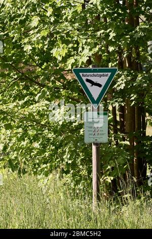 Segno triangolare verde con un'aquila e regole di comportamento per una riserva naturale tedesca, una categoria di fauna selvatica protetta Foto Stock
