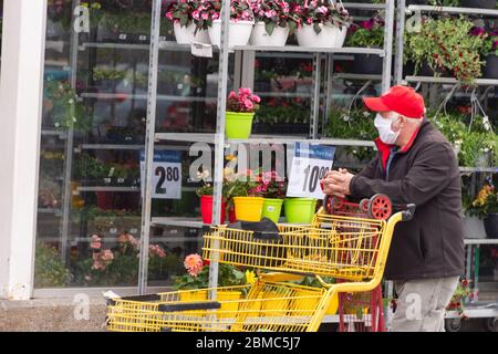 Montreal, CA - 8 maggio 2020 : clienti in una linea fuori dal supermercato. Alcune di esse indossano maschere di protezione Covid-19. Foto Stock