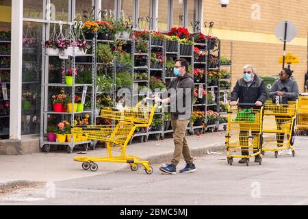 Montreal, CA - 8 maggio 2020 : clienti in una linea fuori dal supermercato. Alcune di esse indossano maschere di protezione Covid-19. Foto Stock