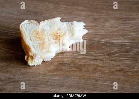 Mezzo mangiato Sandwich gettato sul pavimento. Sandwich scartato. Pane gettato a terra. Gettato nel cibo spazzatura. Concetto. Foto Stock