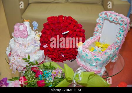 Un mazzo di fiori di cento rose rosse . Grande bouquet di cento grandi rose rosse fiori .Scarpe per bambini rosa . torta da pannolino in un Foto Stock