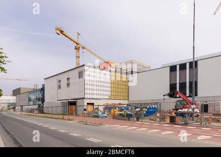 Veldhoven, Paesi Bassi, 8 maggio 2020. Un cantiere di costruzione dei nuovi edifici ASML con una grande gru gialla e materiali da costruzione su un soleggiato Foto Stock