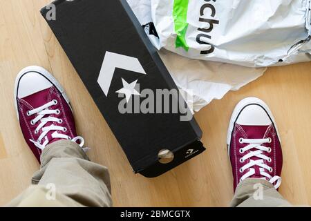 Online scarpe shopping e ordine, e un uomo che prova su nuove scarpe Converse appena consegnato. REGNO UNITO Foto Stock