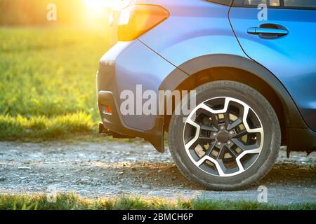 Primo piano della ruota blu fuoristrada su strada di ghiaia. Viaggiando in auto, avventura nella fauna selvatica, spedizione o viaggio estremo su un SUV auto. Offroa Foto Stock