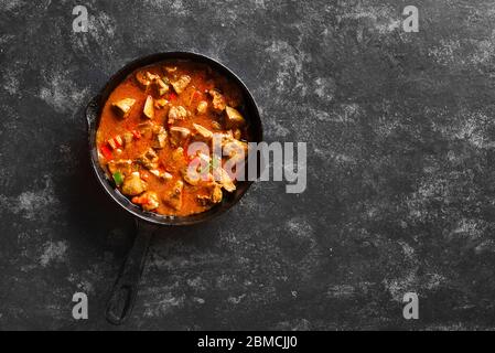 Fegatini di pollo stufati in padella su fondo di pietra nera con spazio libero. Fegati di pollo peri-Peri. Vista dall'alto, disposizione piatta Foto Stock