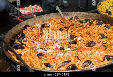 Pesce fresco, pasta di pomodoro, penne cucinate in un grande piatto di wok durante il brunch a buffet all'aperto nel giardino vicino alla piscina. Buffet di cibo fresco Foto Stock