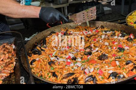 Pesce fresco, pasta di pomodoro, penne cucinate in un grande piatto di wok durante il brunch a buffet all'aperto nel giardino vicino alla piscina. Buffet di cibo fresco Foto Stock