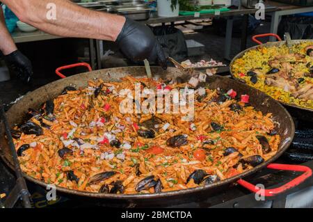 Pesce fresco, pasta di pomodoro, penne cucinate in un grande piatto di wok durante il brunch a buffet all'aperto nel giardino vicino alla piscina. Buffet di cibo fresco Foto Stock