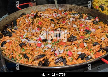 Pesce fresco, pasta di pomodoro, penne cucinate in un grande piatto di wok durante il brunch a buffet all'aperto nel giardino vicino alla piscina. Buffet di cibo fresco Foto Stock