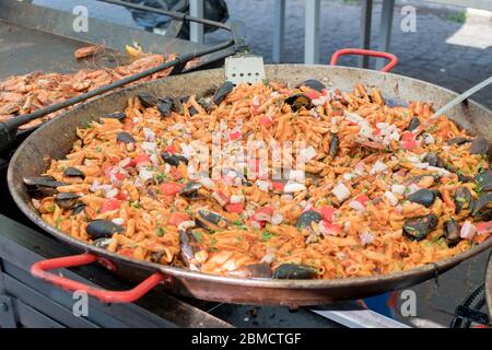 Pesce fresco, pasta di pomodoro, penne cucinate in un grande piatto di wok durante il brunch a buffet all'aperto nel giardino vicino alla piscina. Buffet di cibo fresco Foto Stock