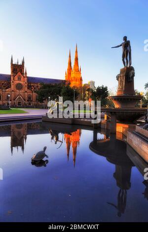 centro di Sydney hyde Park all'alba intorno alla fontana STILL e la cattedrale cattolica contro il cielo blu con riflessione. Foto Stock