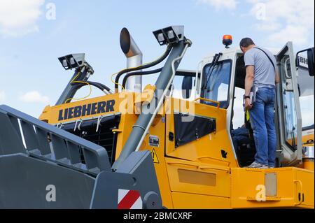 Mosca, Russia - 4 giugno 2016: Due uomini che ispezionano la cabina operatore di 50 tonn Liebherr bulldozer, passando attraverso le funzioni di base apripista. Foto Stock