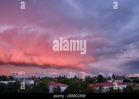 Nuvole di tempesta rosa e viola al tramonto, a Bucarest, Romania, in contrasto con gli edifici esterni luminosi. Foto Stock