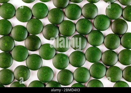 molte compresse verdi di spirulina organica posate ramdomly in uno strato su una superficie bianca piatta Foto Stock