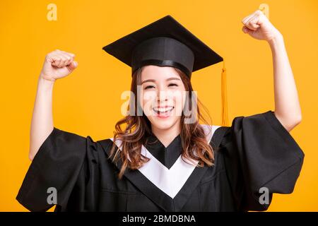 giovane donna in laurea abiti e mostrando il gesto di successo Foto Stock