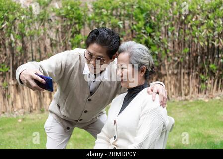Una coppia asiatica anziana sta usando un telefono cellulare per prendere selfie Foto Stock
