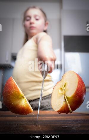 Chef che taglia una mela verde a metà con un grande coltello in movimento.  Spruzzi di acqua e succo volare in diverse direzioni e congelare in aria  Foto stock - Alamy