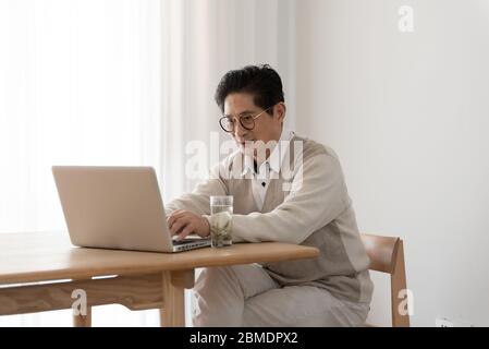Anziani asiatici che utilizzano computer alla scrivania Foto Stock