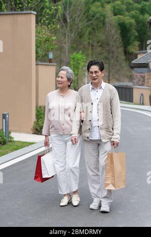 Una coppia asiatica anziana che tiene borse per la spesa nella comunità Foto Stock