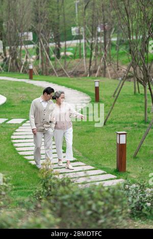 Una coppia asiatica anziana che cammina nel parco Foto Stock