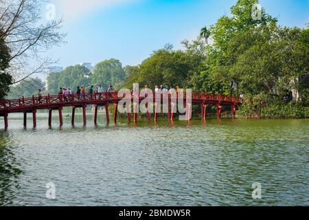 Hanoi Vietnam Ottobre 25 2013; turisti e locali che attraversano il tradizionale stile orientale rosso Huc Bridge sopra Hoan Kiem Lago nel parco della città. Foto Stock