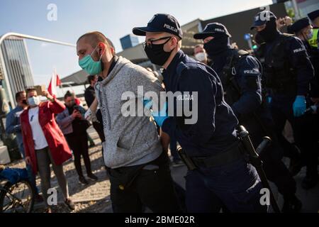 Varsavia, Polonia. 8 maggio 2020. Un protesta arrestato dalla polizia mentre indossa maschere facciali come precauzione contro la diffusione del virus covid 19, durante la dimostrazione. Il gruppo chiamato 'sciopero degli imprenditori' guidato dal candidato presidenziale, Pawel Tanajno si è riunito per protestare per il secondo giorno in un crudo contro il 'congelamento dell'economia' a causa della pandemia del virus della corona. I manifestanti hanno bloccato il traffico nel centro di Varsavia. Numerosi manifestanti sono stati arrestati durante lo sciopero. Credit: SOPA Images Limited/Alamy Live News Foto Stock