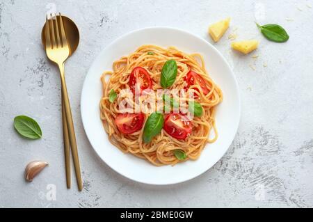 Spaghetti in salsa di pomodoro con formaggio su un piatto bianco su fondo chiaro. Disposizione piatta Foto Stock