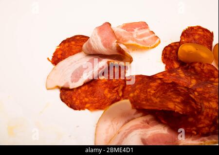 Fette di salsiccia e pancetta e pomodori su sfondo bianco. Primo piano Foto Stock