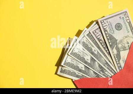 Uno stack di dollari statunitensi, banconote in valuta in una busta di carta rossa aperta, isolato contro yellow.Online Shopping.Wealth e prosperità. Denaro contante in Foto Stock