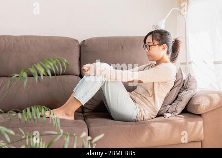 Womain che si stese sul divano pensando e sognando. Coronavirus rimanere quarantena casa. Ragazza sul divano rilassante e meditante Foto Stock