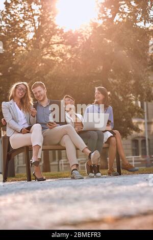 Sorridendo giovani d'affari sulla panchina al parco durante la pausa caffè. Foto Stock