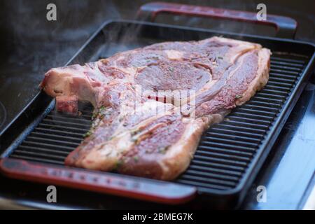 Vista ravvicinata di una bistecca cruda, una tagliata a Sirloin, grigliata su una padella per grigliare Foto Stock