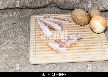 Pancetta tagliata sottile su un asse di legno. Foto Stock