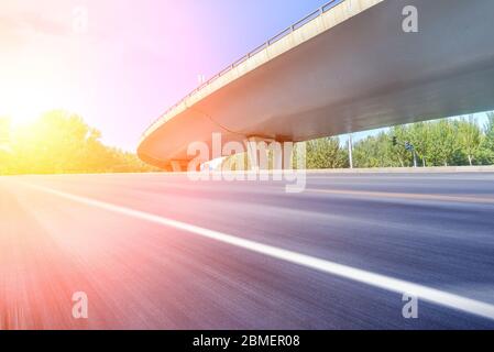 Sotto il cavalcavia, strada asfaltata senza auto, moderno skyline della città come sfondo. Foto Stock