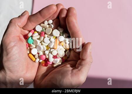 Uomo che tiene pillole su hand.Overdose di farmaco. Un sacco di pillole versate sul tavolo. Tentativo di suicidio. Crisi economica e problemi di medicina. Virus Foto Stock